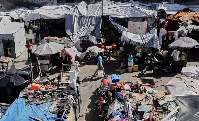 A man carries a buckets of water where families displaced by gang violence are living in Port-au-Prince, Haiti, Wednesday, Aug. 12, 2026. (AP Photo/Odelyn Joseph)