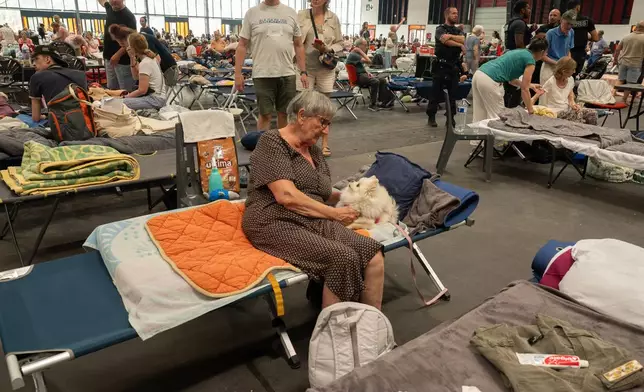 A woman caresses her pet dog at an emergency shelter set up in the Bordeaux Exhibition Centre in Bordeaux, France, for those that had to leave their homes outside town due to the raging wildfires, Sunday, July 26, 2026. (AP Photo/Caroline Blumberg)