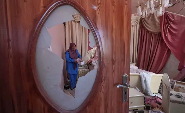 Mahasen Faqih is seen through a shattered glass door as she checks her home, destroyed during the Israeli military operation, after returning to it in Zawtar al-Gharbieh, Lebanon, Tuesday, July 28, 2026. (AP Photo/Hassan Ammar)