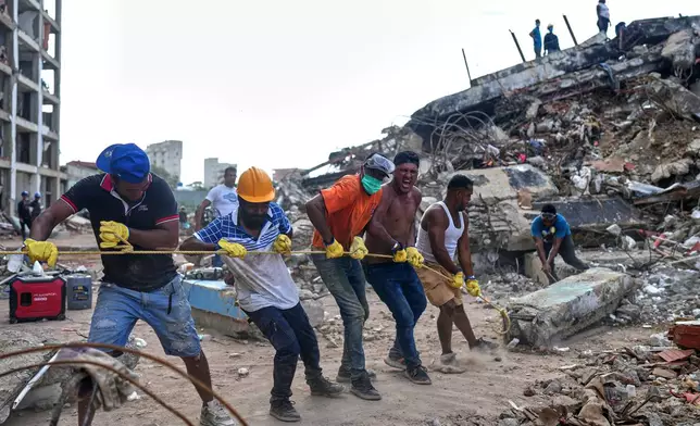 Volunteers pull a rope to remove a debris from a collapsed building by earthquakes in La Guaira, Venezuela, Sunday, July 12, 2026. (AP Photo/Ariana Cubillos)
