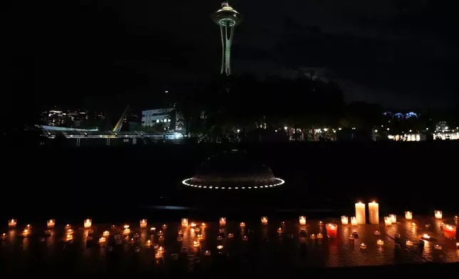 With a backdrop of the Space Needle, candles are seen lighted during the vigil for victims the day after a shooting at Seattle Center during the Bite of Seattle food festival, Monday, July 27, 2026, in Seattle. (AP Photo/Lindsey Wasson)