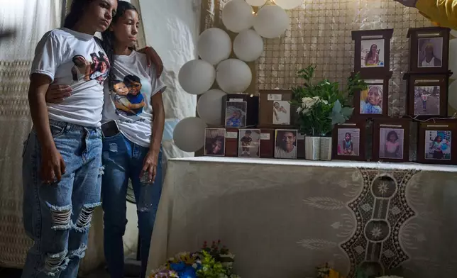 Noemi Marrero, left, who lost her children Mathias and Wilker, stands with her sister close to the urns with their ashes and other relatives members during a prayer for relatives of the victims of the June 24 earthquakes, in La Guaira, Venezuela, Saturday, Aug. 8, 2026. (AP Photo/Ariana Cubillos)