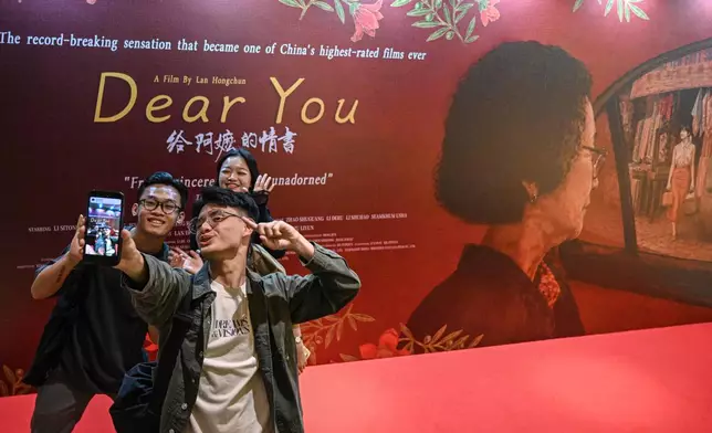 In this photo released by Xinhua News Agency, viewers take selfie in front of an advertisement for the Chinese film "Dear You" during its premiere in Jakarta, Indonesia, on Aug. 5, 2026. (Agung Kuncahya B./Xinhua via AP)
