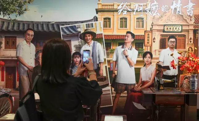 In this photo released by Xinhua News Agency, a woman takes photos during the special screening of Chinese film "Dear You" in Kuala Lumpur, Malaysia, on June 15, 2026. (Chen Zeguo/Xinhua via AP)