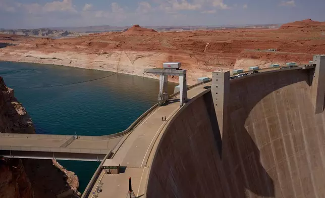 People walk across the Glen Canyon Dam near Lake Powell at the Glen Canyon National Recreation Area, Tuesday, July 14, 2026, near Page, Nev. (AP Photo/John Locher)