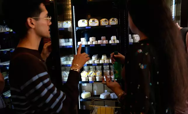 An employee gives information to a customer at Le Butter Shop, the first shop devoted entirely to butter in Paris, France, Tuesday Aug. 25, 2026. (AP Photo/Christophe Ena)