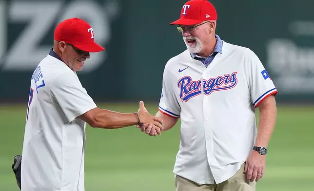Former Texas Rangers Ivan Rodriguez, left, and Rusty Greer shake hands before a baseball game between the Los Angeles Angels and Texas Rangers, Saturday, Aug. 22, 2026, in Arlington, Texas. (AP Photo/LM Otero)