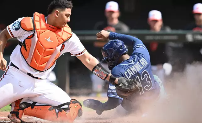 Tampa Bay Rays' Junior Caminero (13) slides into home plate to score as Baltimore Orioles catcher Samuel Basallo, left, tags in the sixth inning of a baseball game Sunday, Aug. 23, 2026, in Baltimore. (AP Photo/Gail Burton)