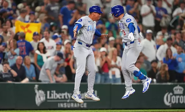 Chicago Cubs' Alex Bregman, right, celebrates with third base coach Quintin Berry after hitting a solo home run to tie the game during the ninth inning of a baseball game against the Seattle Mariners, Friday, Aug. 21, 2026, in Seattle. (AP Photo/Lindsey Wasson)