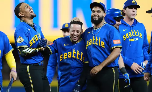 Seattle Mariners' Leo Rivas, center, celebrates with teammates Julio Rodríguez, left, and Seranthony Domínguez, third from left, after his walk-off RBI single in the 10th inning to win a baseball game against the Chicago Cubs, Friday, Aug. 21, 2026, in Seattle. (AP Photo/Lindsey Wasson)