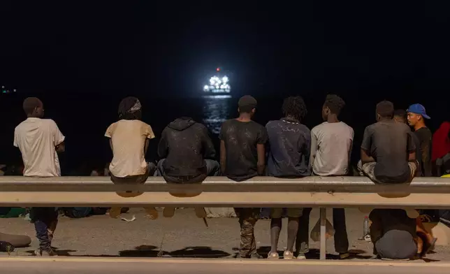 Migrants who crossed into Spain from Morocco gather on a beach in the Spanish enclave of Ceuta, Sunday, Aug. 2, 2026. (AP Photo/Antonio Sempere)