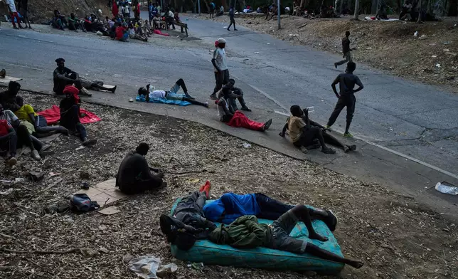 Migrants who crossed into Spain from Morocco sit outside the temporary immigrant stay center (CETI) in the Spanish enclave of Ceuta, Sunday, Aug. 2, 2026. (AP Photo/Bernat Armangue)