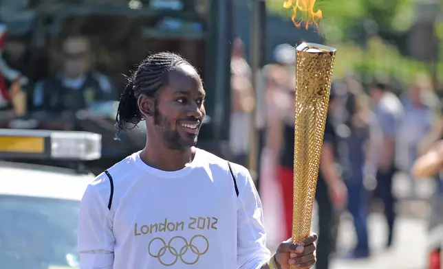 Torchbearer Jason Arday carries the Olympic Flame on the Torch Relay leg between Sutton and Merton, in London, July 23, 2012. (Joe Giddens/LOCOG/PA via AP)