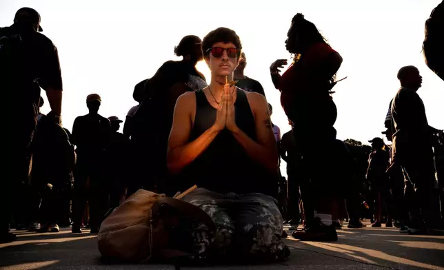 A demonstrator holds a paper crane while kneeling in front of the Lincoln Memorial before the March on Washington, Friday, Aug. 28, 2026, in Washington. (AP Photo/Julia Demaree Nikhinson)