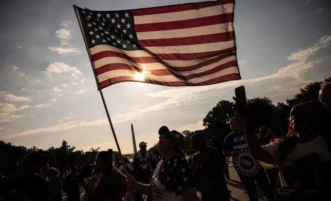 A demonstrator holds an American flag near the Lincoln Memorial before the March on Washington, Friday, Aug. 28, 2026, in Washington. (AP Photo/Julia Demaree Nikhinson)