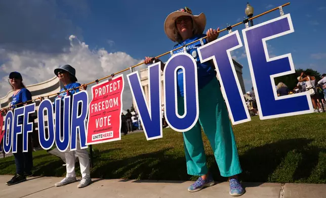 Demonstrators holds a sign during the March on Washington, Friday, Aug. 28, 2026, near the Lincoln Memorial in Washington. (AP Photo/Julia Demaree Nikhinson)