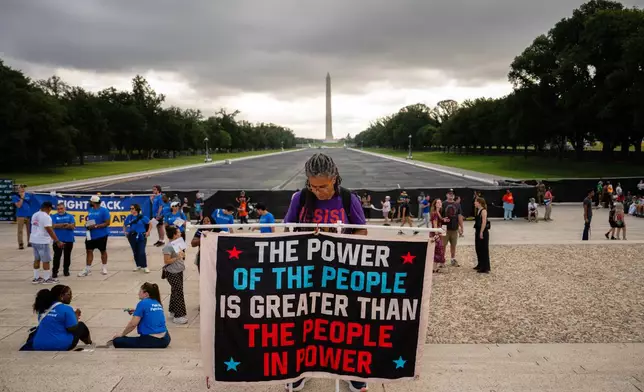 A demonstrator holds a sign in front of the Lincoln Memorial Reflecting Pool during the March on Washington, Friday, Aug. 28, 2026, in Washington. (AP Photo/Julia Demaree Nikhinson)