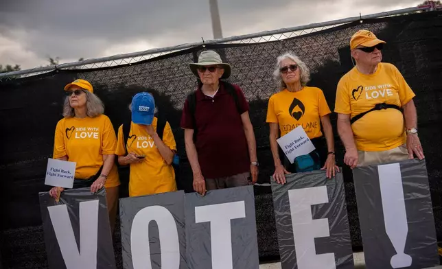 Demonstrators hold signs spelling out "VOTE!" in front of fencing surrounding the Lincoln Memorial Reflecting Pool, during the March on Washington, Friday, Aug. 28, 2026, in Washington. (AP Photo/Julia Demaree Nikhinson)