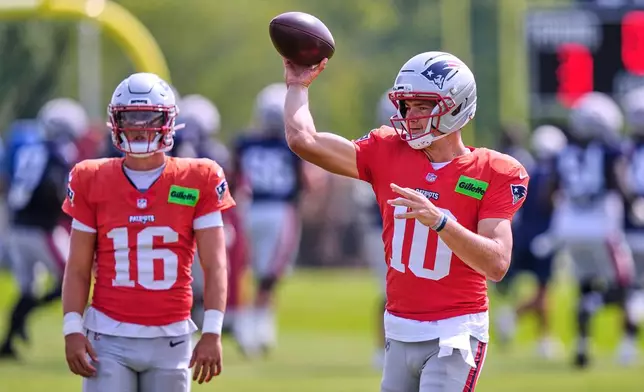 New England Patriots quarterback Drake Maye (10) throws a pass as Tommy DeVito (16) looks on during a NFL football training camp, Tuesday, Aug. 11, 2026, in Foxborough, Mass. (AP Photo/Charles Krupa)