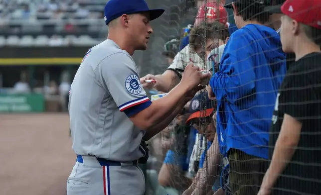 Texas Rangers shortstop Corey Seager signs autographs before a baseball game against the Chicago White Sox Tuesday, Aug. 25, 2026, in Chicago. (AP Photo/David Banks)