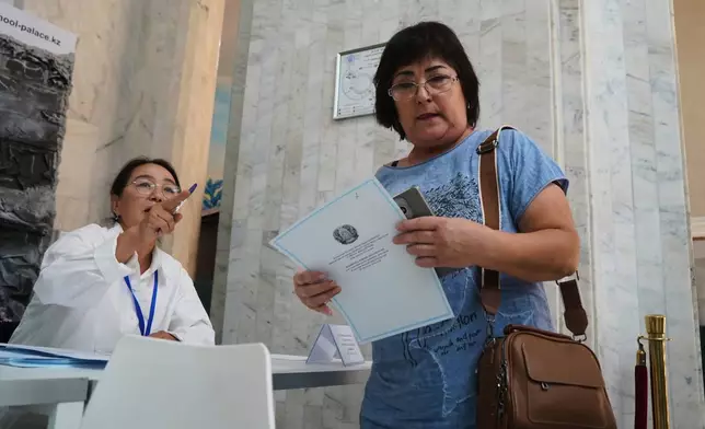 A woman holds her ballot at a polling station during early parliamentary elections in Almaty, Kazakhstan, Sunday, Aug. 23, 2026. (AP Photo/Vladimir Tretyakov)
