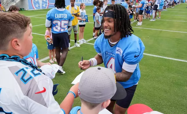 Tennessee Titans wide receiver Wan'dale Robinson, right, signs autographs for fans after practice during the NFL football team's training camp Saturday, Aug. 1, 2026, in Nashville, Tenn. (AP Photo/George Walker IV)