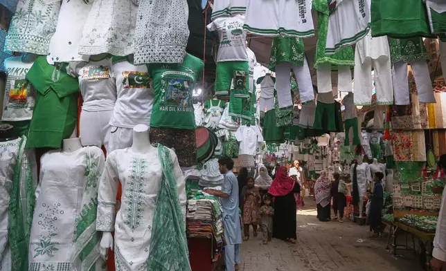 People visit a market to buy clothes specially prepared in national colors for the Pakistan's Independence Day celebrations, in Peshawar, Pakistan, Thursday, Aug. 13, 2026. (AP Photo/Muhammad Sajjad)