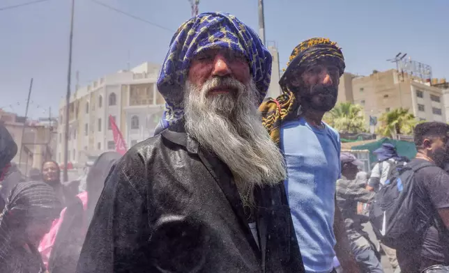Water is sprayed over Shiite pilgrims to cool them as they make their way to Karbala for Arbaeen, the annual Shiite commemoration marking 40 days after Ashura, in Najaf, Iraq, Friday, July 31, 2026. (AP Photo/Ammar Khalil)