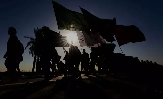 The sun rises as Shiite pilgrims march on their way, to Karbala, to observe Arbaeen that marks the end of a 40-day mourning period following the Day of Ashura, in Najaf, Iraq, Tuesday, July 28, 2026. (AP Photo/Anmar Khalil)