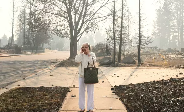 Miriam Sim, 76, reacts as she walks through the burned remains of her neighborhood after a wildfire hit the northern part of Spokane, Wash., Monday, Aug. 3, 2026. (AP Photo/Lindsey Wasson)