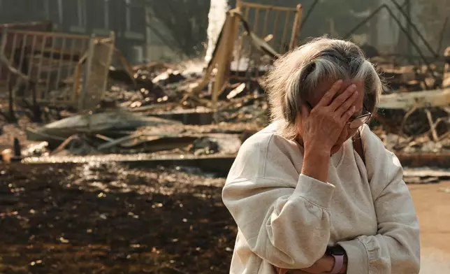 Miriam Sim, 76, reacts while talking about her neighborhood largely burning to the ground after a wildfire hit the northern part of Spokane, Wash., Monday, Aug. 3, 2026. (AP Photo/Lindsey Wasson)