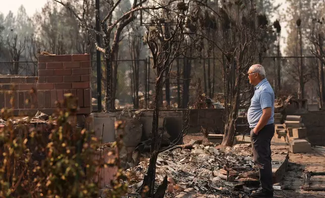 Daniel Sim, 76, views the remains of his destroyed house after a wildfire hit the northern part of Spokane, Wash., Monday, Aug. 3, 2026. (AP Photo/Lindsey Wasson)