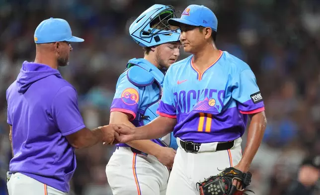 Colorado Rockies manager Warren Schaeffer, left, takes the ball from starting pitcher Tomoyuki Sugano, right, as he is pulled from the mound while catcher Hunter Goodman looks on in the seventh inning of a baseball game against the Kansas City Royals Friday, July 31, 2026, in Denver. (AP Photo/David Zalubowski)