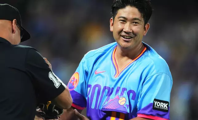 First base umpire Vic Carapazza, left, checks the glove and cap of Colorado Rockies starting pitcher Tomoyuki Sugano after he retired the Kansas City Royals in the fourth inning of a baseball game Friday, July 31, 2026, in Denver. (AP Photo/David Zalubowski)
