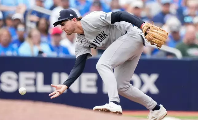 New York Yankees third baseman Ryan McMahon barehands the ball before throwing it to first base but Toronto Blue Jays' Charles McAdoo was safe during the fourth inning of a baseball game in Toronto, Sunday, Aug. 16, 2026. (Nathan Denette/The Canadian Press via AP)