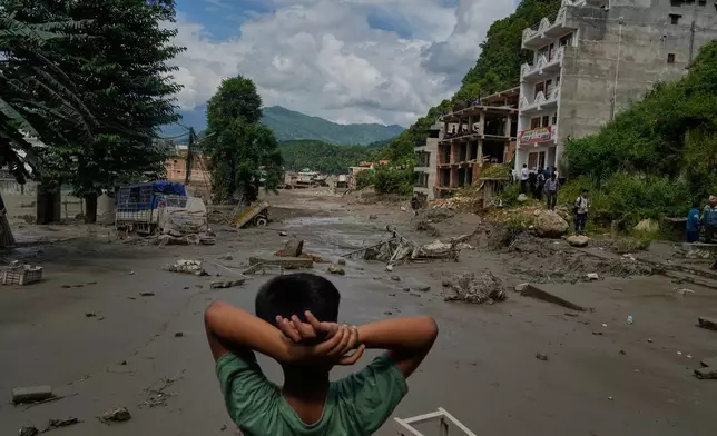 A boy looks at the devastation caused by flash flooding along the Trishuli River in Nepal's Nuwakot district, Wednesday, Aug. 26, 2026. (AP Photo/Niranjan Shrestha)