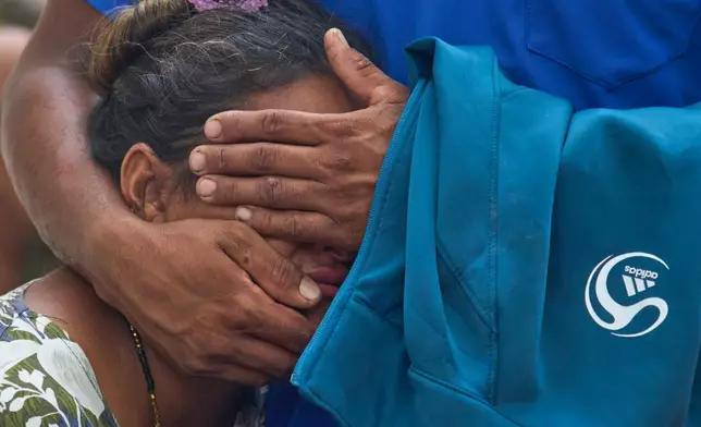 A woman consoles a relative as they wait for news of family members missing after flash flooding along the Trishuli River in Nepal's Nuwakot district, Wednesday, Aug. 26, 2026. (AP Photo/Niranjan Shrestha)