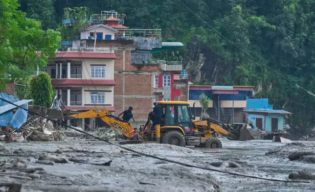 Rescuers use earthmovers to reach submerged houses after flash flooding along the Trishuli River in Nepal's Nuwakot district, Wednesday, Aug. 26, 2026. (AP Photo/Niranjan Shrestha)