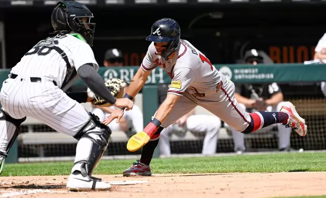 Atlanta Braves' Mauricio Dubón, right, scores past Chicago White Sox catcher Drew Romo (36) during the third inning of a baseball game, Thursday, Aug. 20, 2026, in Chicago. (AP Photo/Matt Marton)