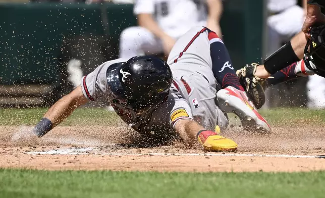 Atlanta Braves' Mauricio Dubón scores past the Chicago White Sox catcher Drew Romo during the third inning of a baseball game, Thursday, Aug. 20, 2026, in Chicago. (AP Photo/Matt Marton)