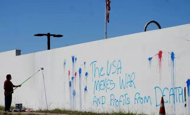 A worker paints to remove protest graffiti on a wall of the U.S. Embassy in Brasília, Brazil, Thursday, Aug. 13, 2026. (AP Photo/Eraldo Peres)
