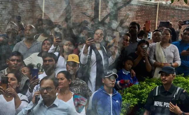 Family members, friends and supporters photograph a coffin containing the body of Pur Bahadur Gurung, the Nepali mountain guide who died along with nine other climbers in an avalanche on Pakistan's Broad Peak, at Tribhuvan International Airport in Kathmandu, Nepal, Thursday, Aug. 6, 2026. (AP Photo/Niranjan Shrestha)