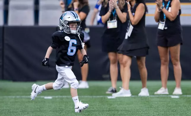 Make-a-wish recipient Asher Harvey runs on to the field during the NFL football team's fan fest Friday, July 31, 2026, in Charlotte, N.C. (AP Photo/Scott Kinser)
