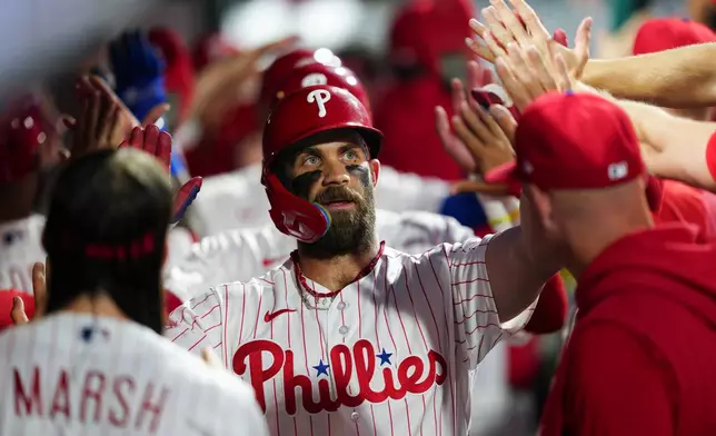 Philadelphia Phillies' Bryce Harper celebrates in the dugout after hitting a three-run home run off St. Louis Cardinals pitcher Ryan Fernandez during the sixth inning of a baseball game, Saturday, Aug. 22, 2026, in Philadelphia. (AP Photo/Derik Hamilton)