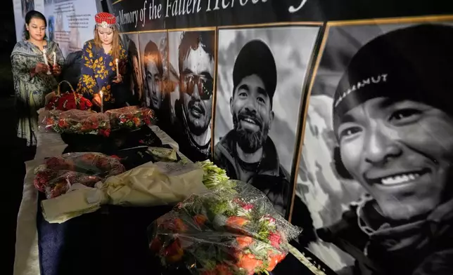 Woman place candles next to pictures of climbers who lost their lives on Broad Peak, during a candlelight vigil in their memory, in Islamabad, Pakistan, Tuesday, Aug. 11, 2026. (AP Photo/Anjum Naveed)