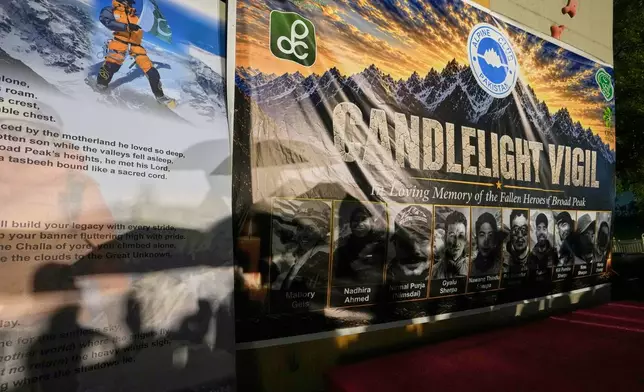 Participant's shadows visible over an poster with the pictures of 10 climbers who lost their lives on Broad Peak during a candlelight vigil in their memory, in Islamabad, Pakistan, Tuesday, Aug. 11, 2026. (AP Photo/Anjum Naveed)