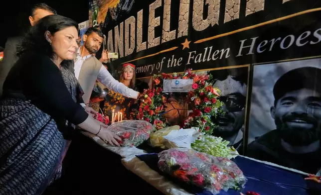 Nepalese Ambassador to Pakistan Rita Dhital, left, and others place flowers next to pictures of climbers who lost their lives on Broad Peak, during a candlelight vigil in their memory, in Islamabad, Pakistan, Tuesday, Aug. 11, 2026. (AP Photo/Anjum Naveed)