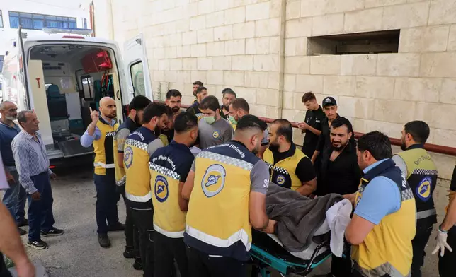 Members of the White Helmets carry the body of Mohammad Ghamira, a former White Helmets volunteer who died shortly after his release from jail, before his burial in the village of al-Haffa, Latakia province, Syria, Monday, Aug. 17, 2026. (AP Photo)
