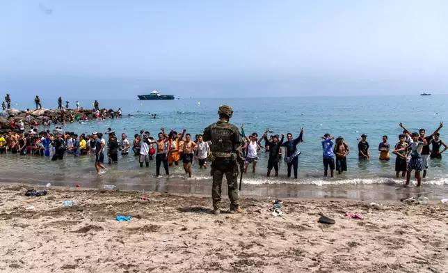Spanish army soldiers block access to the beach for people crossing from Morocco into the Spanish enclave of Ceuta, Friday, July 31, 2026. (AP Photo/Antonio Sempere)