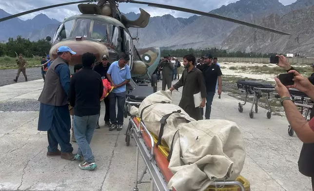 Pakistani army soldiers and volunteers unload from a helicopter the bodies of climbers, that were recovered from Broad Peak nearly a week after an avalanche swept away a 10-member international expedition, upon arrival at a military base in Skardu, in northern Pakistan, Thursday, Aug. 6, 2026. (AP Photo/ M.H. Balti)